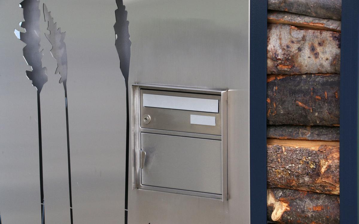Edelstahl-Stellwand mit Briefkasten und Holzstapel