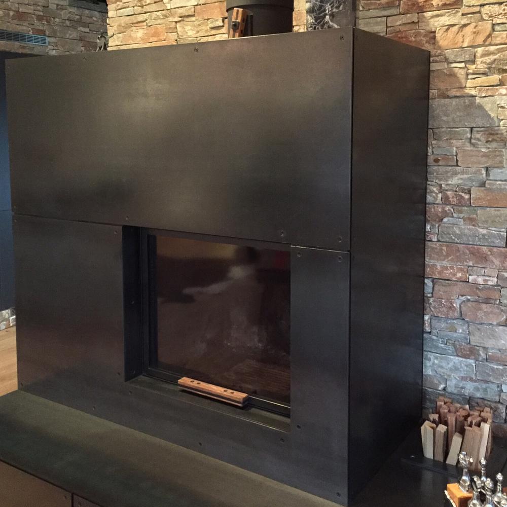 Cheminée mit Verkleidung aus geöltem Schwarzblech und Holzfach
