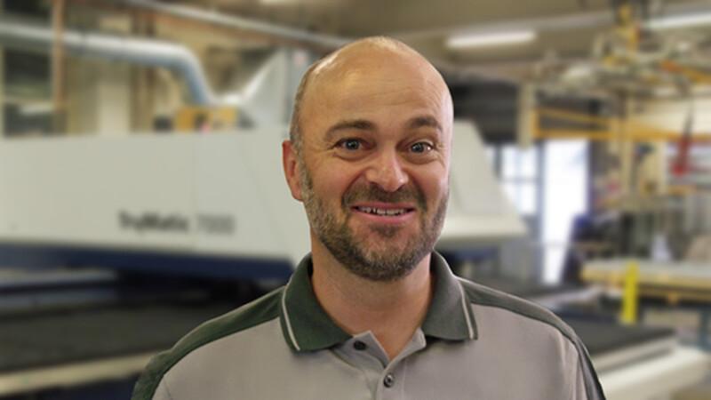 Patrick Züger, Geschäftsleiter, in der Werkstatt vor einer Laserschneidanlage